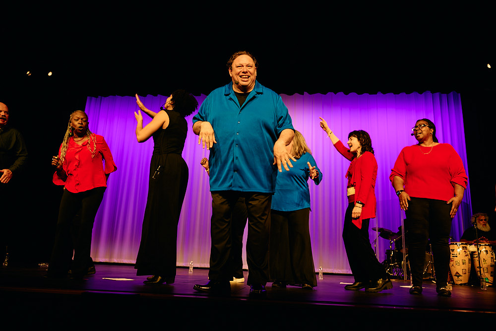 The Exult Choir lined up on stage under red lighting.